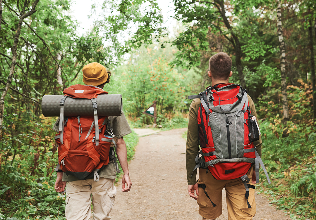 Men with backpacks walking along forest path